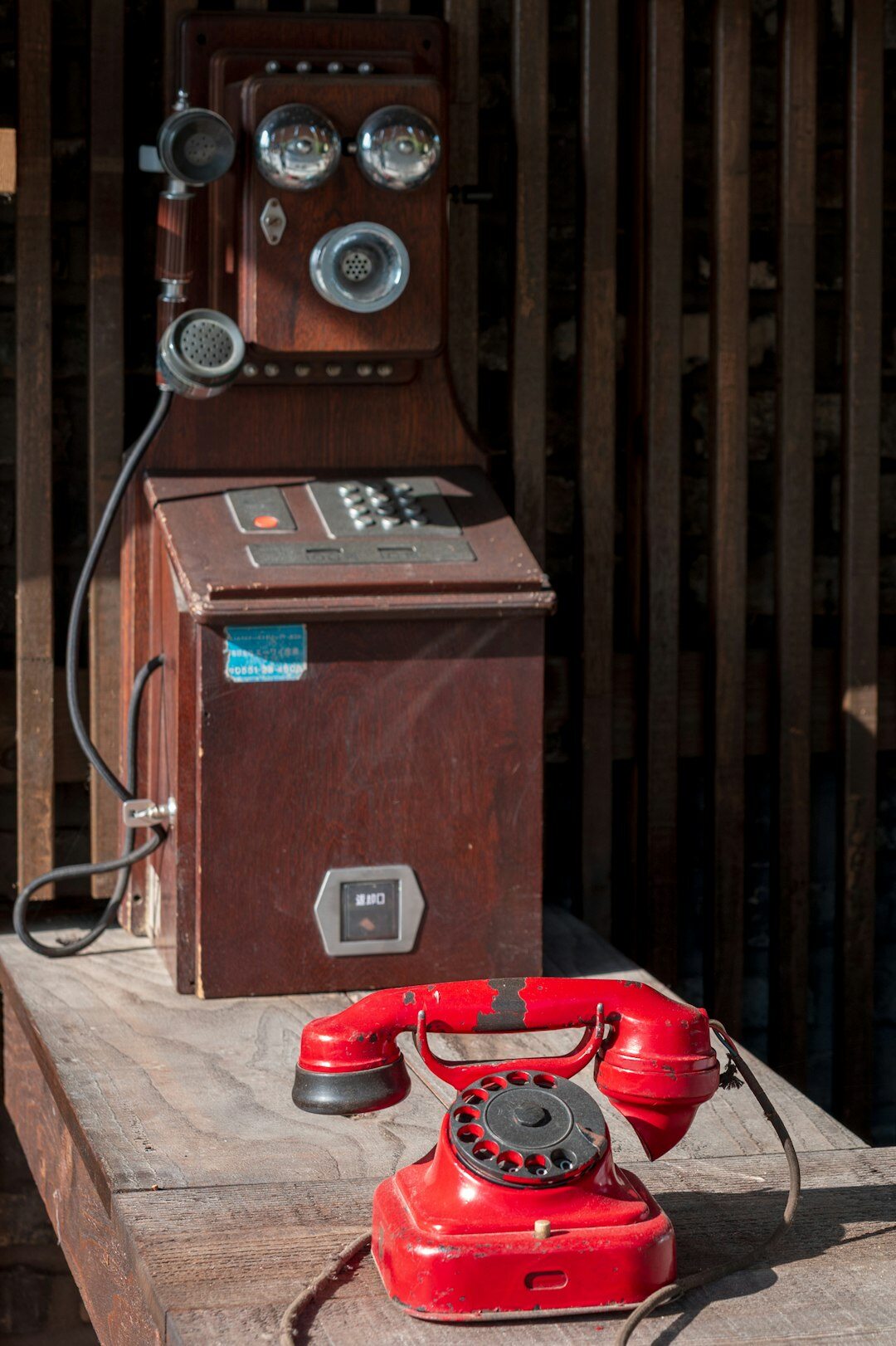 Vintage rotary telephone and typewriter on a wooden desk